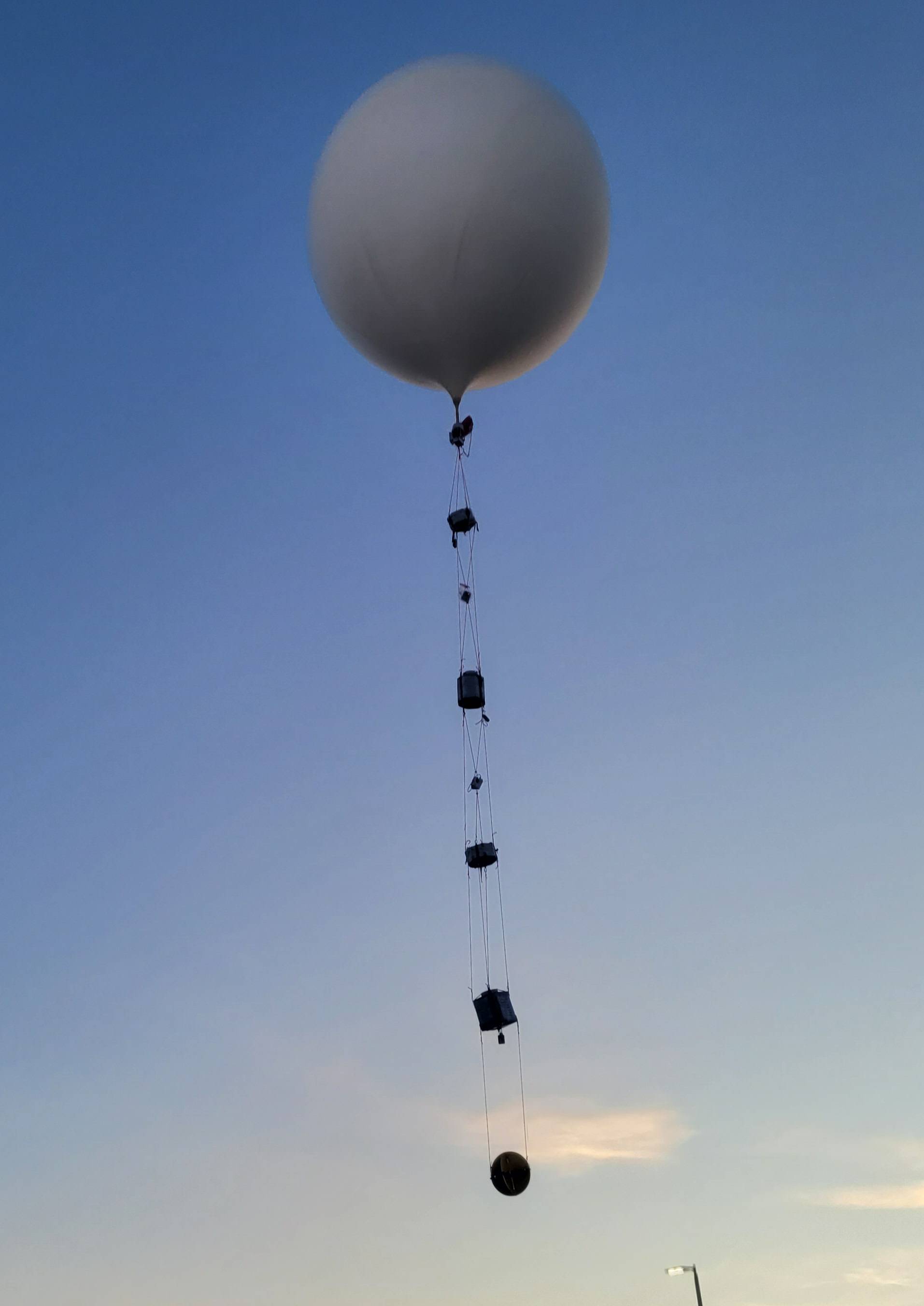 A picture of a balloon with cords bellow attaching to payloads.